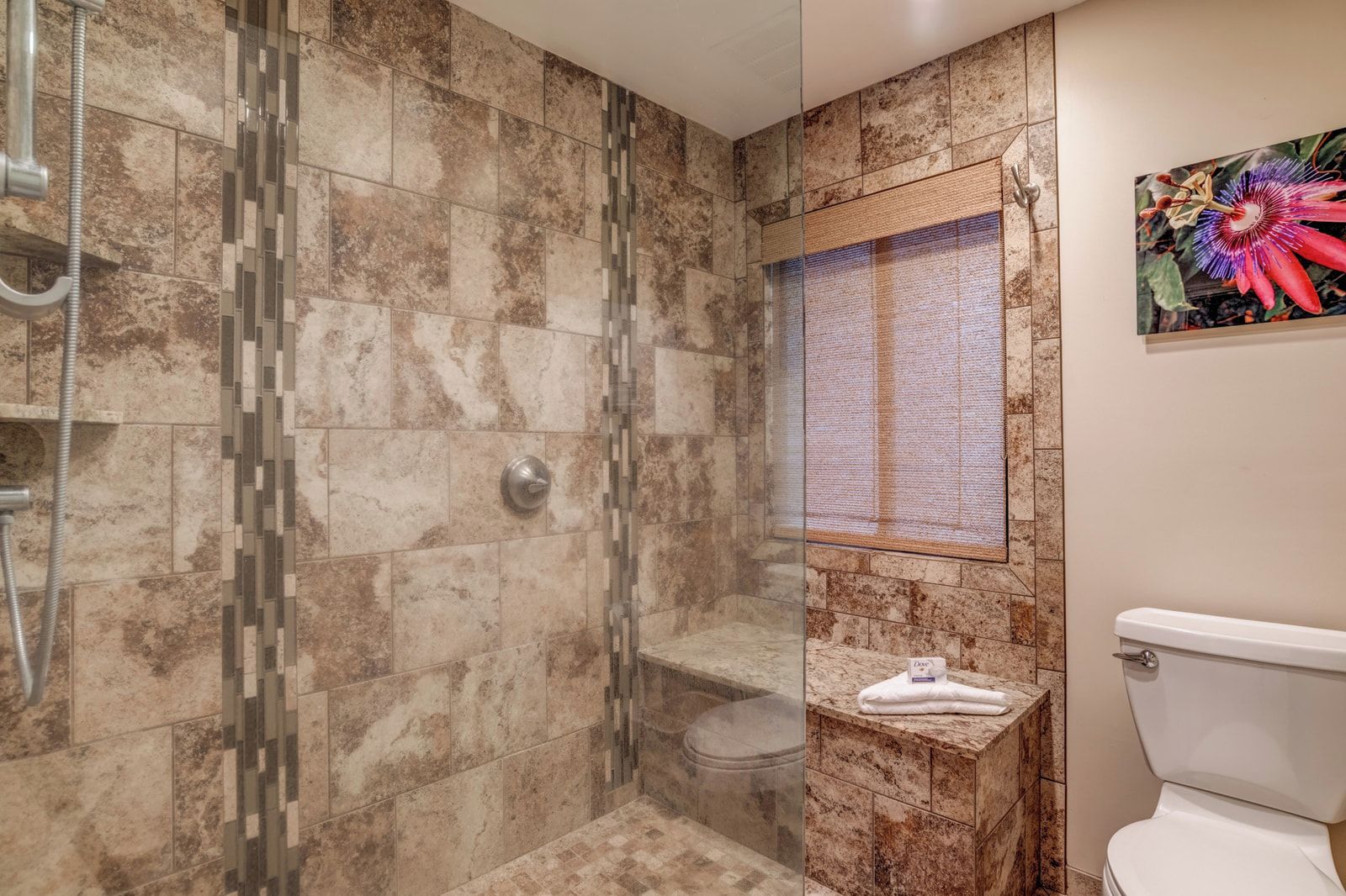 A bathroom with a shower, toilet, and a window with a decorative panel.