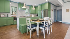 A modern kitchen with green cabinets, white dining chairs, and a central island. - Spacious Modernized Historic Home 3 Minute Walk from Square (Georgetown)
