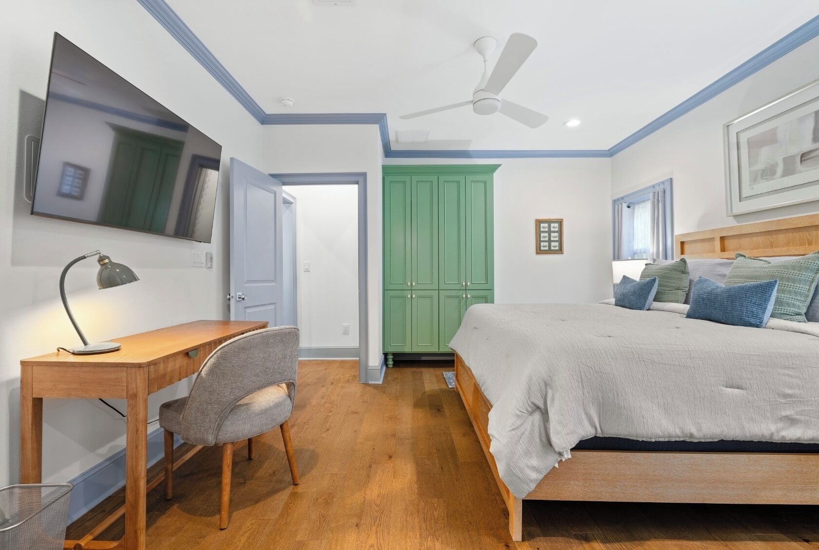 A bedroom with a bed, desk, chair, and a ceiling fan.