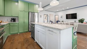 A modern kitchen with green cabinets, a stainless steel refrigerator, and a marble countertop. - Spacious Modernized Historic Home 3 Minute Walk from Square (Georgetown)