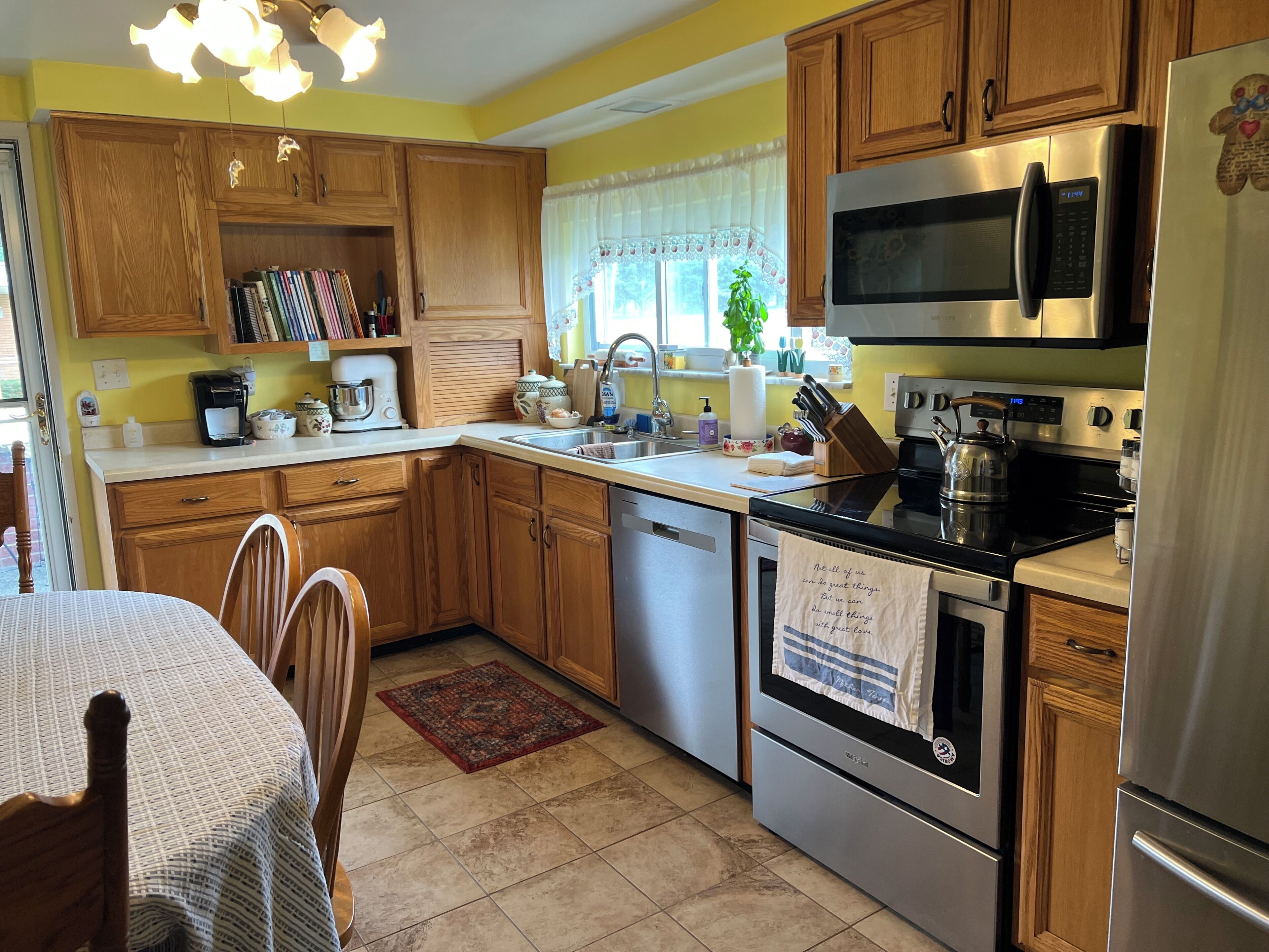A kitchen with wooden cabinets, a stainless steel refrigerator, a microwave, and an oven.