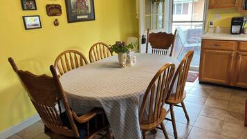 Un coin repas avec une table ronde, six chaises en bois, un vase de fleurs et des tableaux encadrés accrochés au mur.