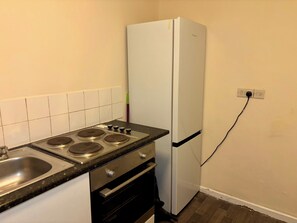Une petite cuisine équipée d’une cuisinière, d’un évier, d’un four et d’un réfrigérateur blanc.
