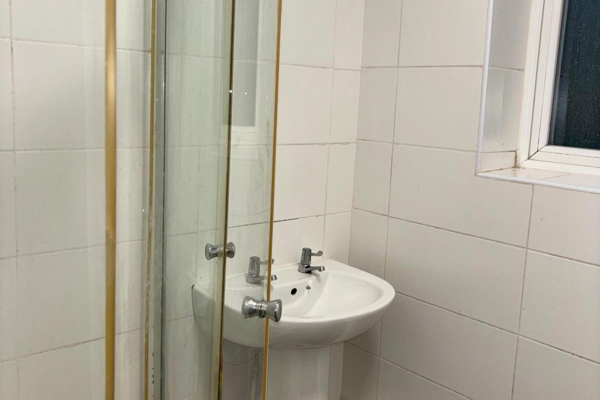 A bathroom with a white sink, a mirror, and a window.
