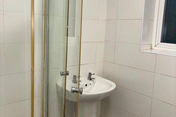 Une salle de bain avec un lavabo blanc, un miroir et une fenêtre.