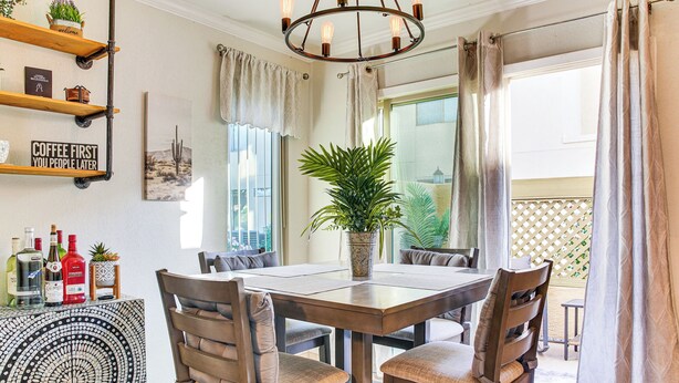 A dining area with a wooden table and chairs, a potted plant, and a wall-mounted shelf with various items. - Bring Your Pet! Snowbird Haven w/ Community Pool! (Scottsdale)