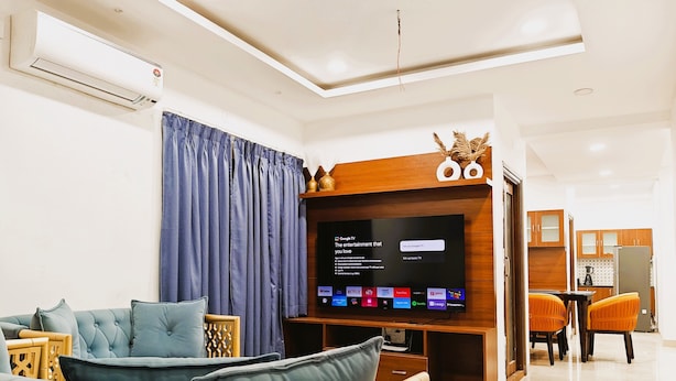 Una sala de estar moderna con un televisor de pantalla plana, un sofá y un comedor con sillas.