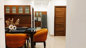 Una cocina moderna con armarios de madera, una mesa de comedor con sillas naranjas y una encimera negra.