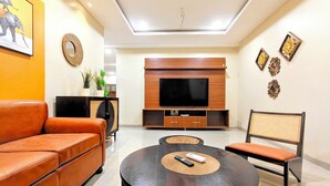 Una sala de estar moderna con un sofá de cuero, una mesa de centro redonda, un televisor y decoración en la pared.