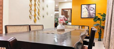 A dining area with a large table, multiple chairs, a ceiling fan, and decorative wall art.
