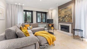 Een moderne woonkamer met een grijze modulaire bank, een open haard en een groot abstract schilderij aan de muur.