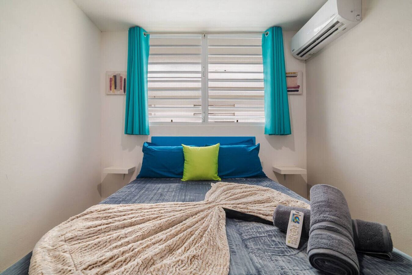 Une chambre à coucher avec un lit, des oreillers, une couverture et un climatiseur.