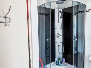 Une douche fermée par des parois en verre, équipée d’un pommeau de douche à main, d’un autre pommeau de douche à main et d’un pommeau de douche fixé au mur.