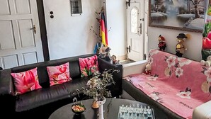 A living room with a black sofa, a coffee table, a chess set, and a painting on the wall. - Stunning  villa for 4 people with WIFI, pool, TV and pets allowed (Rumburk)