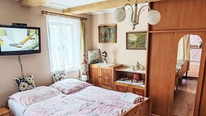 A bedroom with a bed, wooden wardrobe, a television, and a window with curtains. - Stunning  villa for 4 people with WIFI, pool, TV and pets allowed (Rumburk)