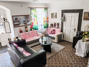 Un salon avec un canapé, une table basse, un tapis à motifs, une porte et une fenêtre avec des rideaux.