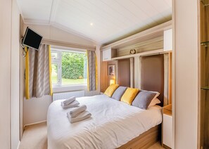 A bedroom with a bed, a TV, a window with curtains, and a built-in wardrobe. - 2 bedroom accommodation in Bala, (Bala,)