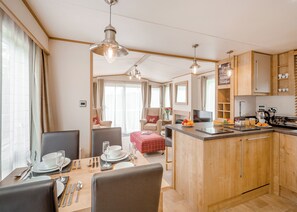 A compact kitchen with wooden cabinets, a dining area with a table set for two, and a kitchenette. - 2 bedroom accommodation in Bala, (Bala,)