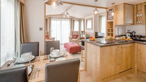 A compact kitchen with wooden cabinets, a dining area with a table set for two, and a kitchenette. - 2 bedroom accommodation in Bala, (Bala,)