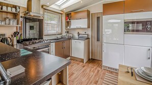A modern kitchen with a central island, built-in appliances, and a skylight. - 2 bedroom accommodation in Bala, (Bala,)