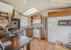 A modern kitchen with a central island, built-in appliances, and a skylight. - 1 bedroom accommodation in Bala, (Bala,)