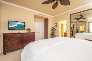 Ein Hotelzimmer mit Bett, Schminktisch, Fernseher, Deckenventilator und Spiegel.