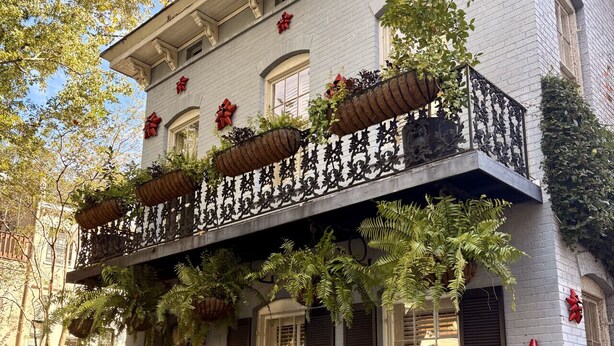 A two-story building with a balcony adorned with red bows and potted plants. - Hawkins House - Historic Savannah Stay near Forsyth Park with Designer Interiors & Heated Pool (Savannah)