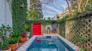 A pool area with a checkered floor, a red door, and potted plants. - Hawkins House - Historic Savannah Stay near Forsyth Park with Designer Interiors & Heated Pool (Savannah)