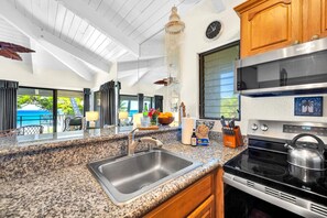 A kitchen with granite countertops, stainless steel appliances, and a view of the ocean. - Napili Point | Oceanfront 4 BR, Sleeps 12 | Car Incl. w/ 6+ Nights | NAP ML-2432 by KBM (Lahaina)