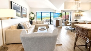 Ein modernes Wohnzimmer mit Sofa, Sessel und Essbereich.