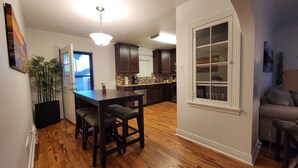 A modern kitchen with dark wood cabinets, a central island, and a dining area with bar stools. - Clean quiet and comfortable home welcomes you (Colorado Springs)