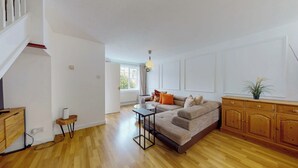 A spacious living room with a sofa, a coffee table, and a wooden cabinet. - 3 bed house with parking near Tower Bridge (London)