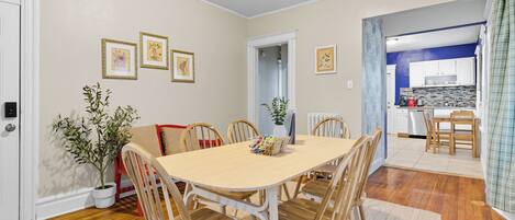 Un coin repas avec une table et des chaises en bois, une plante en pot et des tableaux encadrés au mur.