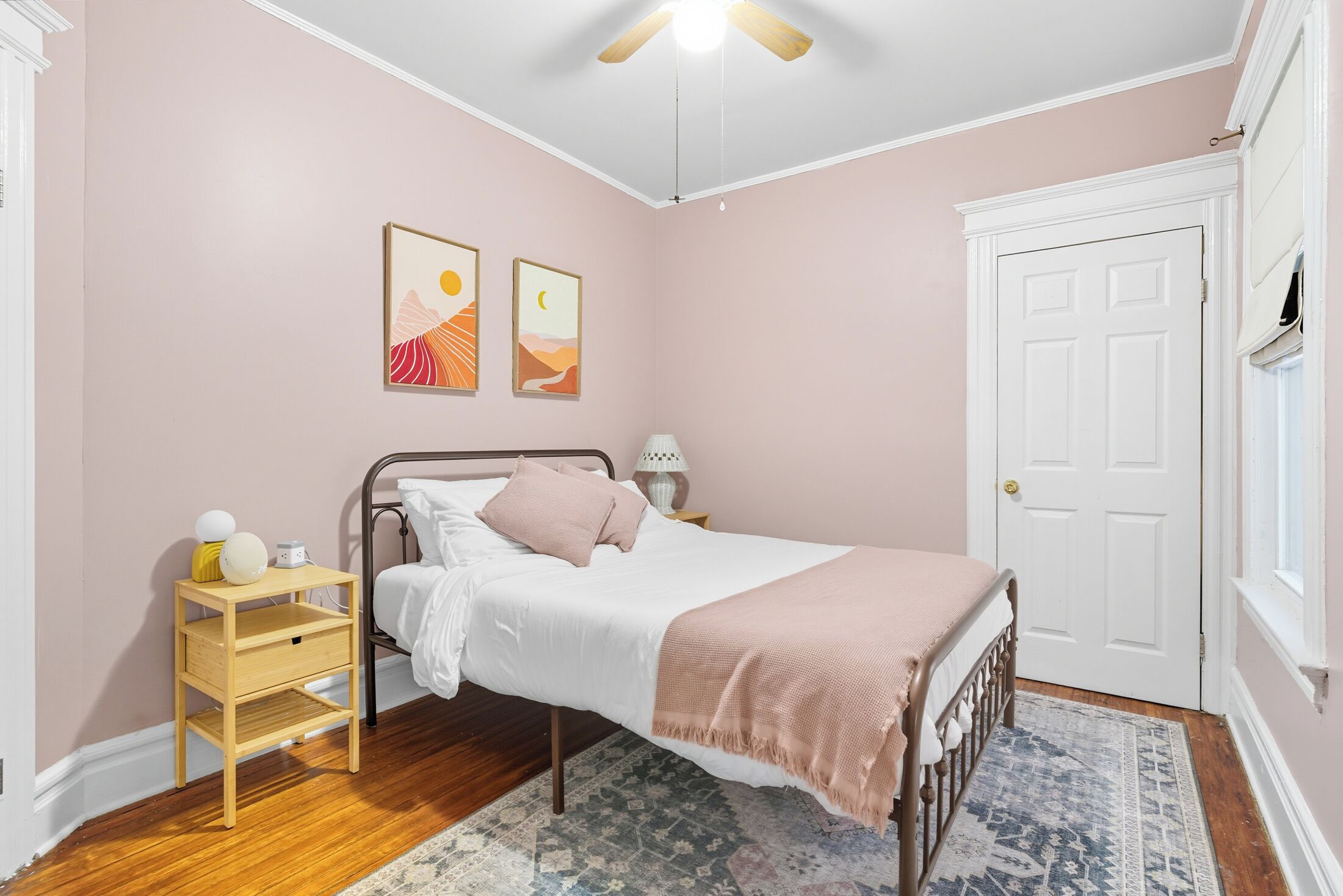 Un dormitorio con cama, mesita de noche y puerta.