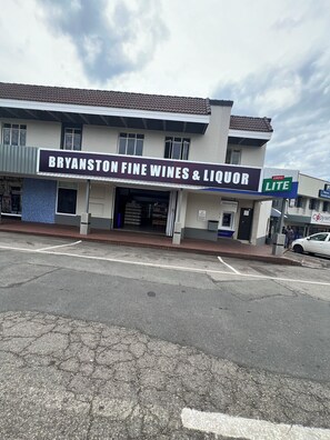 A storefront with a sign for 'Bryanston Fine Wines & Liquor' and a 'Castle Lite' sign. - Serene, Bryanston + free pizza (Sandton)