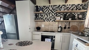 Ett kök med ett rutmönstrat stänkskydd, en diskmaskin, en tvättmaskin och ett kylskåp.
