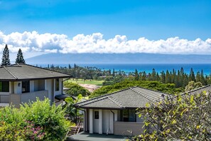 A coastal property with a view of the ocean, featuring a house with a tiled roof and a garden.
