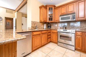 A kitchen with granite countertops, wooden cabinets, a stainless steel oven, and a microwave.