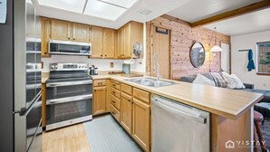 Een praktische keuken met houten kastjes, een inbouwoven, een magnetron en een vaatwasser.
