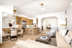 A modern living room with a sofa, coffee table, and a dining area with chairs and a table. - Kapalua Golf | Golf View 4 BR, Sleeps 12 | Car Incl. w/ 6+ Nights | KGV ML-2210 by KBM (Lahaina)