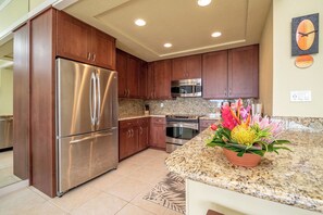 Una cocina moderna con electrodomésticos de acero inoxidable, encimeras de granito y armarios de madera.