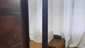 A room with a wooden floor, a brown sofa, a white curtain, and a large mirror. - Charming 1BR Apartment In Top Location (Vienna)