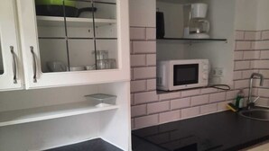 A compact kitchen with white cabinets, a microwave, a coffee maker, and a washing machine. - Charming 1BR Apartment In Top Location (Vienna)