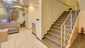 A modern interior with a staircase, a sofa, a small table, and a potted plant. - Le Mysuru Palace (Mysore)
