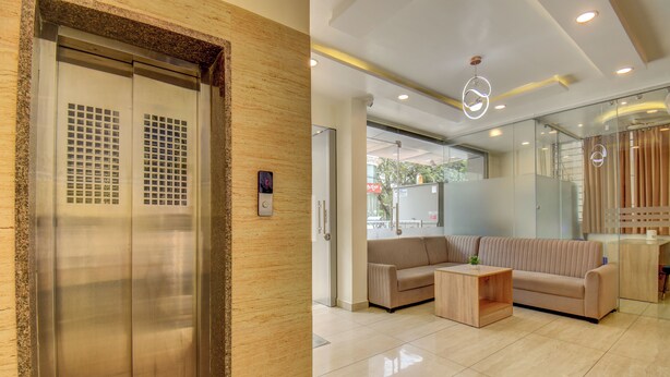 A modern lobby with a reception desk, a sofa, and an elevator. - Le Mysuru Palace (Mysore)