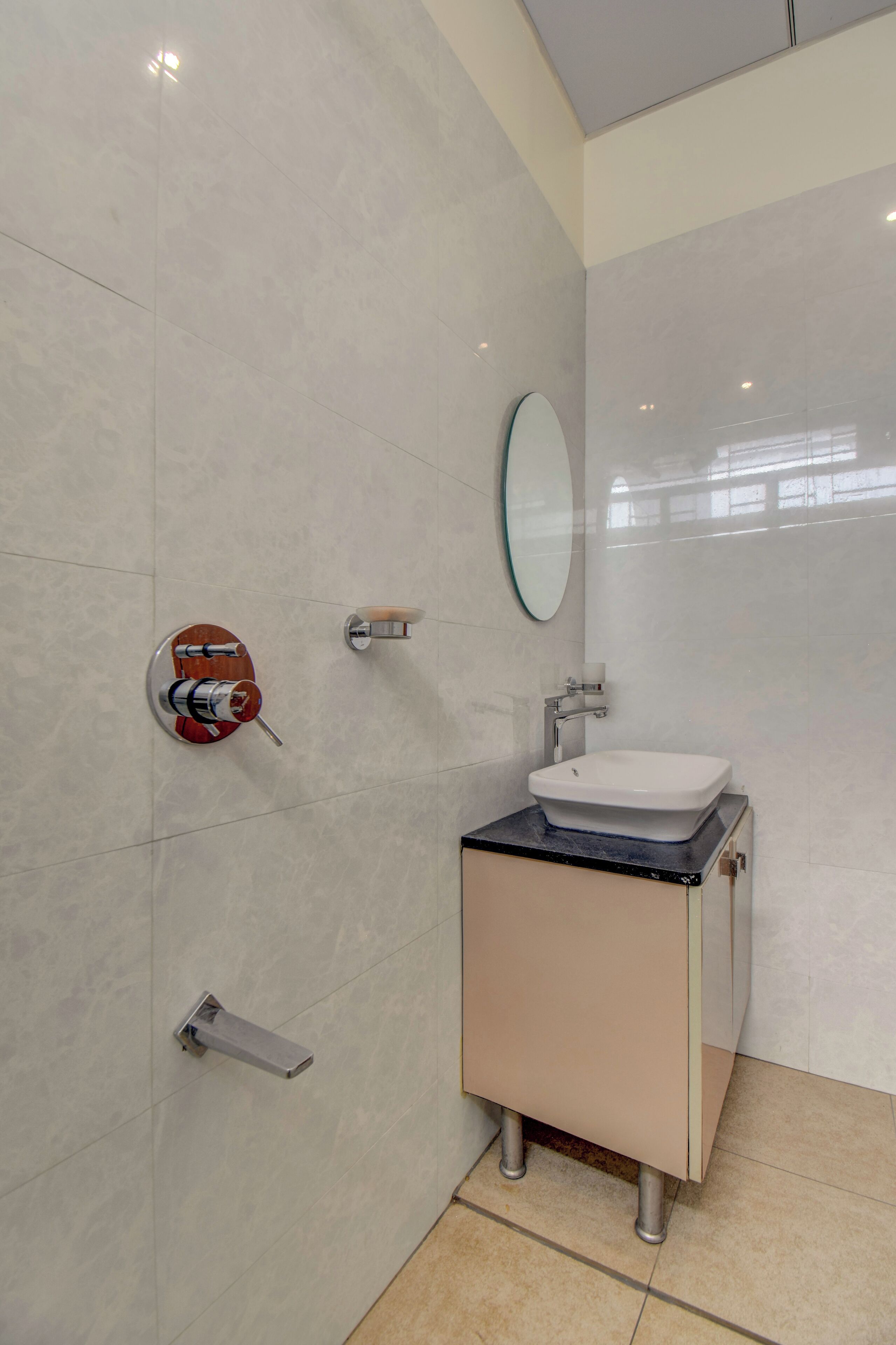 Un baño moderno con un lavamanos blanco, un espejo y un dispensador de toallas en la pared.