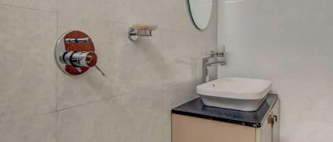 Une salle de bain moderne avec un lavabo blanc, un miroir et un distributeur de serviettes fixé au mur.