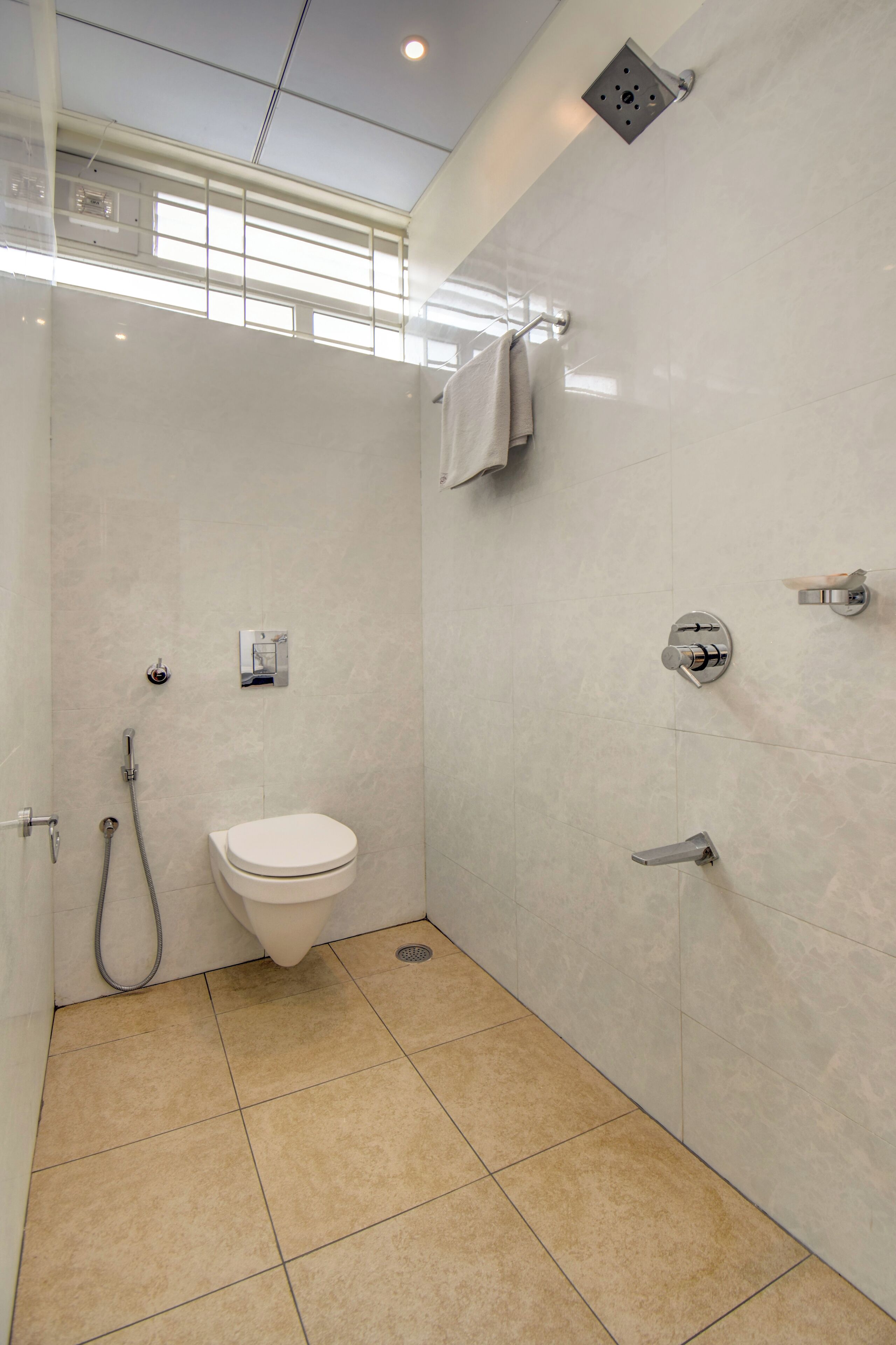 A modern bathroom with a toilet, shower, and a towel hanging on the wall.