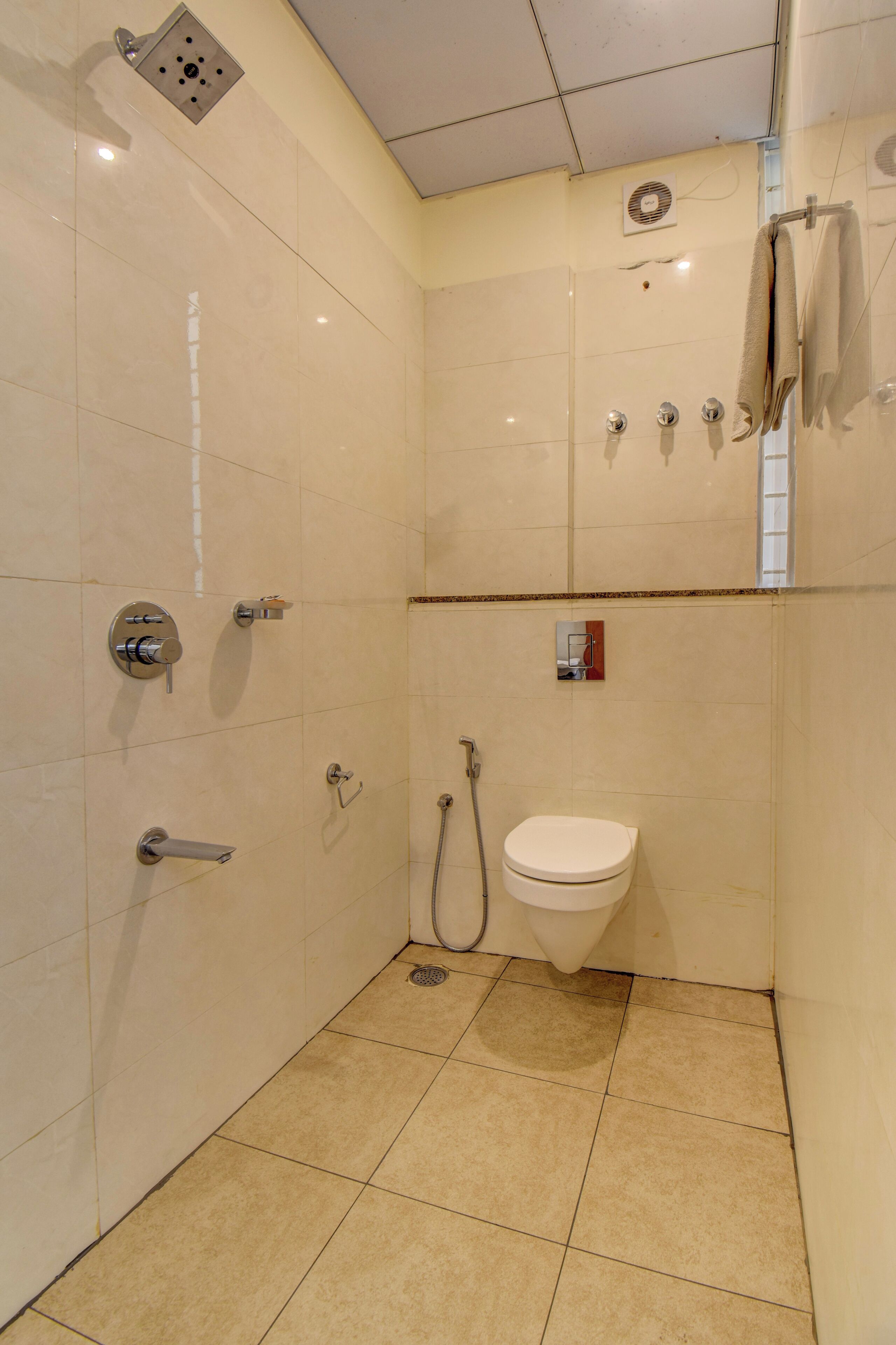 A small, tiled bathroom with a toilet, shower, and sink.