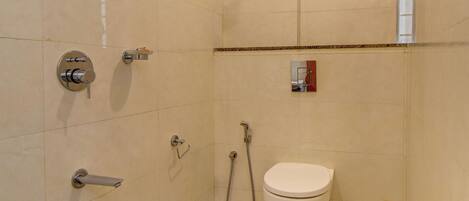 A small, tiled bathroom with a toilet, shower, and sink.
